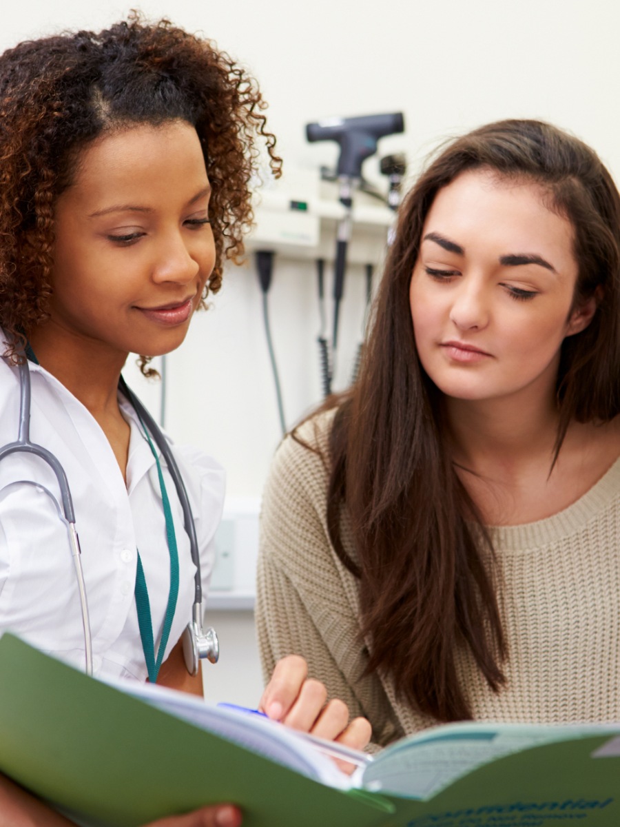 A doctor or nurse, looking at a green folder with a patient also looking at it.