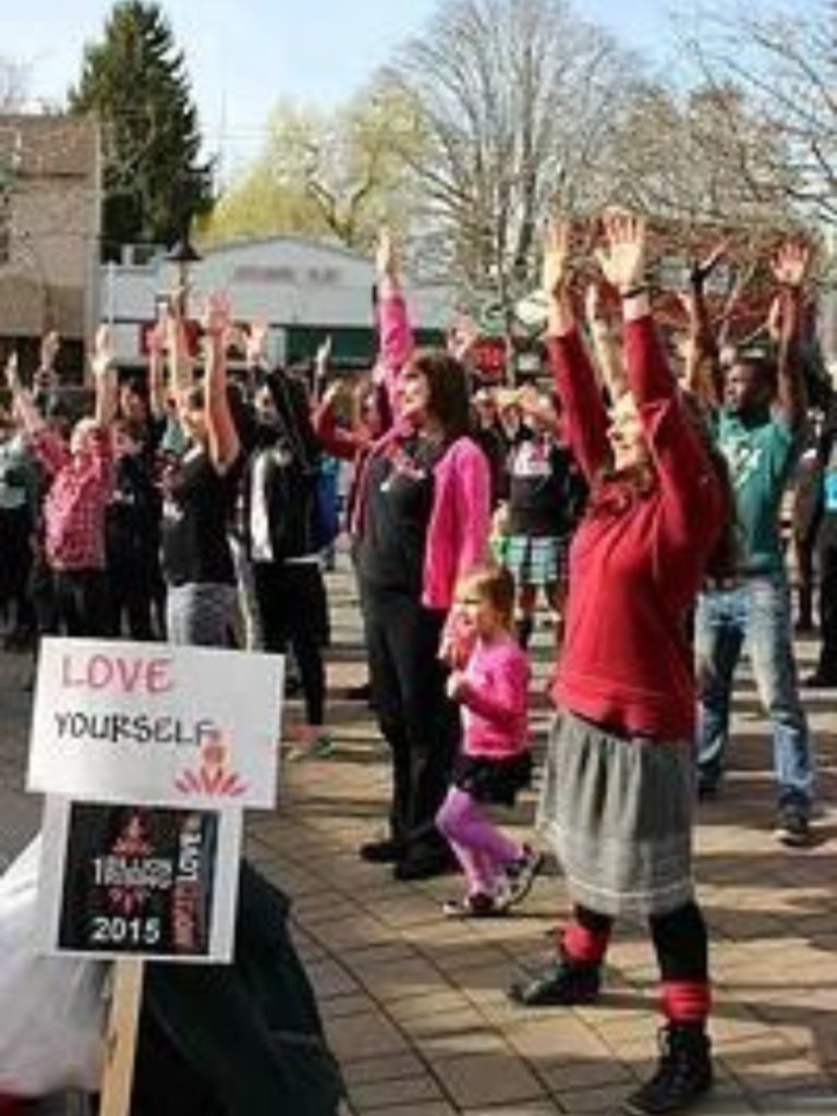 People standing with their arms up in a town event.