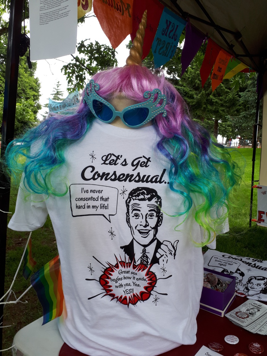 A white t-shirt saying "Let's Get Confessional" with a rainbow wig and teal sunglasses.
