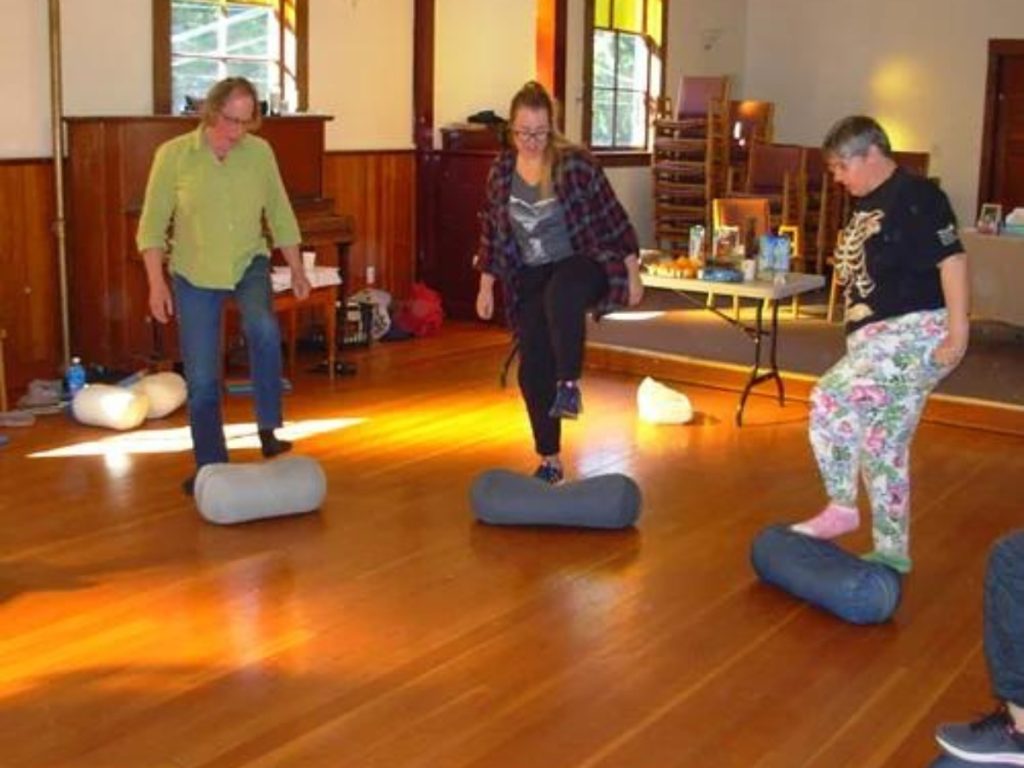 Three people rolling round objects with their feet.