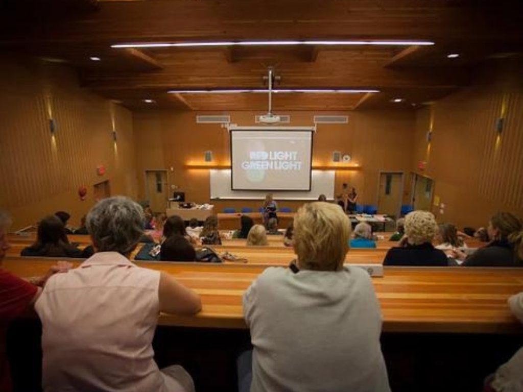 A lecture hall with wooden finishings and a projector in front.